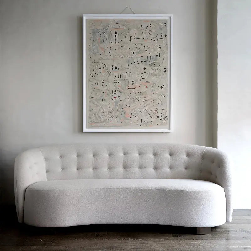 White couch against a well with a picture hanging on the wall behind.